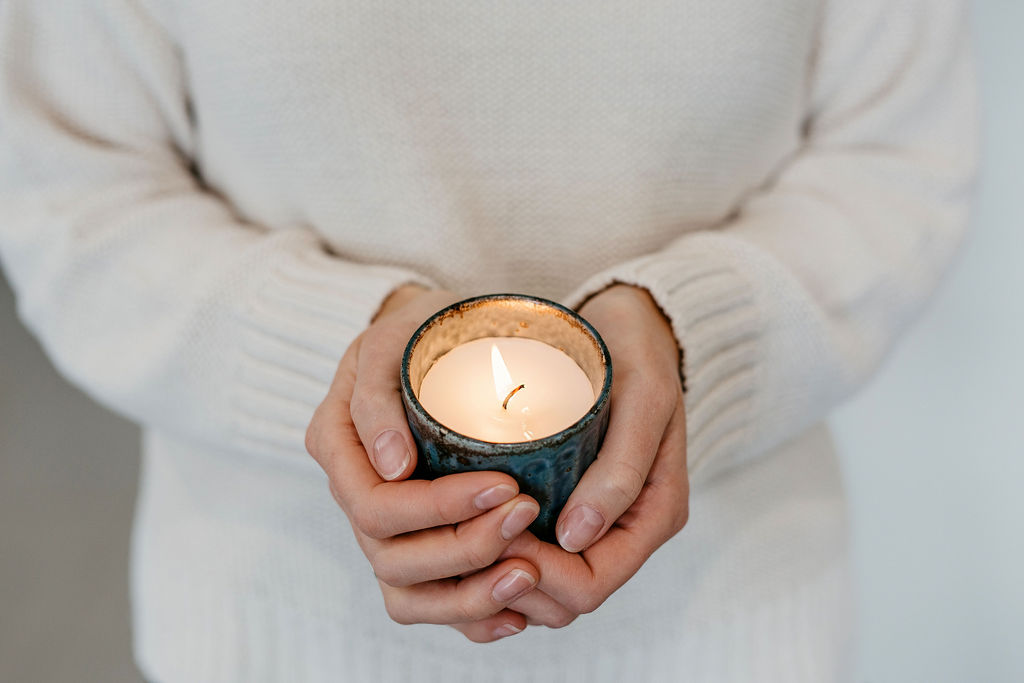 Person in a white sweater holding a lit candle