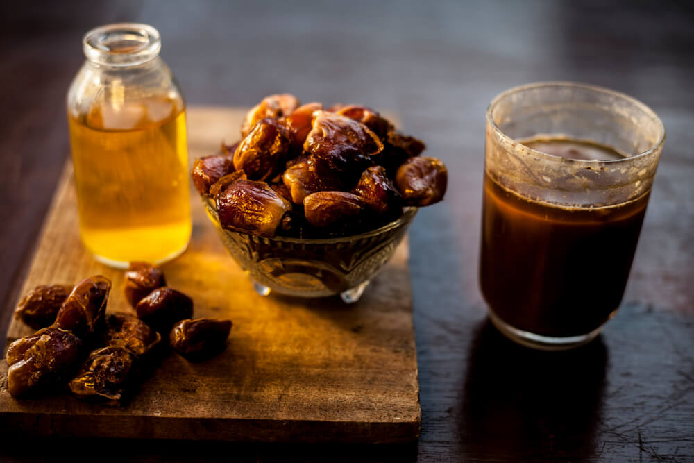 dates syrup in a glass with raw dried dates on the side